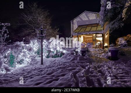 Night time snow and sparkling LED evening lights illuminate the Yorkshire smallholding farm house Stock Photo