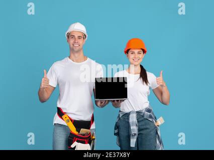 Man And Woman In Hardhats Holding Laptop With Black Screen, Mockup Image Stock Photo