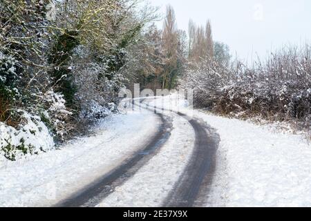 Vehicle tracks on a winding, snow covered country lane in Clifford, West Yorkshire Stock Photo