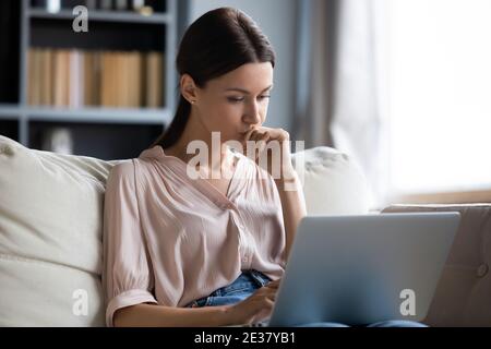 Close up thoughtful upset woman looking at laptop screen Stock Photo