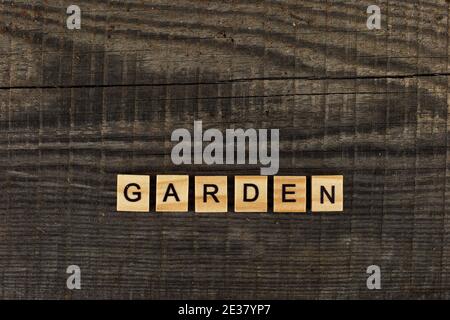 Wooden letter in the word Garden, lies on a dark old wood board Stock Photo