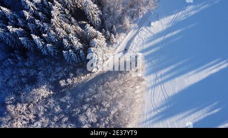 Aerial drone shot of snowy forest path in winter in Bavaria Stock Photo