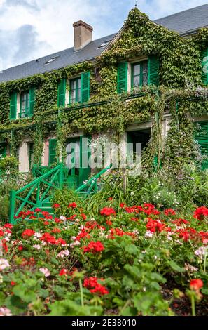 The house of the famous French painter Claude Monat in Giverny is surrounded by Geraniums and other flowers, with the facade covered by ivy; France Stock Photo
