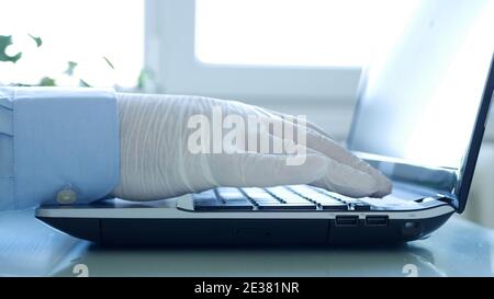 Closeup Image with Hands Wearing Protective Gloves Using the Laptop Keypad Stock Photo