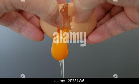 Close Up Image with Hands Breaking a Fresh Chicken Egg in the Kitchen Preparing the Morning Omelette for the Breakfast Stock Photo