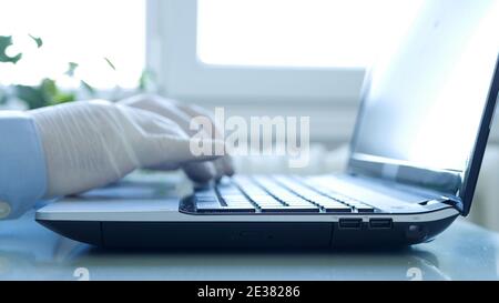 Closeup Image with Hands Wearing Protective Gloves Using the Laptop Keypad Stock Photo