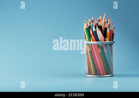 Colorful pencils in a metal jar on a blue background. The concept of creativity, the space Stock Photo