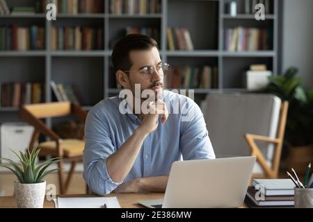 Distracted from work pensive young man looking in distance. Stock Photo