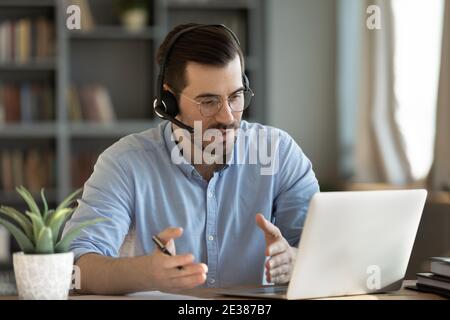 Concentrated skilled millennial caucasian businessman holding negotiations meeting online. Stock Photo