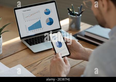 Focused young businessman analyzing marketing research results on gadgets. Stock Photo