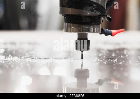 End mill processes a plastic sheet on a CNC milling machine, close-up photo with selective soft focus Stock Photo