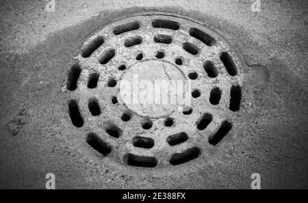Dirty round sewer manhole installed in gray street pavement Stock Photo