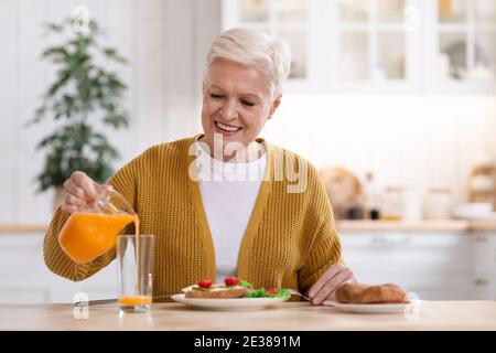 Joyful senior woman having healthy lunch at home Stock Photo