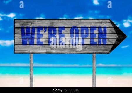 We're open wooden sign with on a beach background Stock Photo