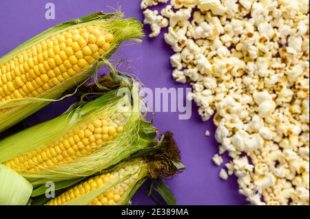 Corncobs and popcorn isolated on purple background Stock Photo