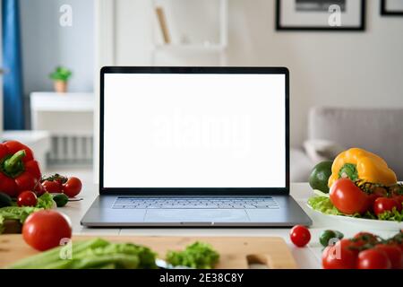 Laptop computer with mockup white screen on food vegetable background. Stock Photo