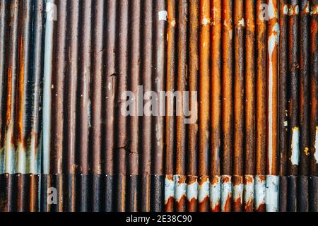 Rusty cracked corrugated metal wall, composed of small sheets. Stock Photo