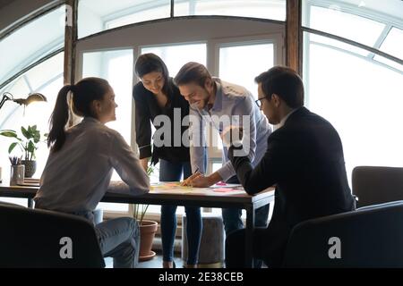 Diverse employees team working on project documents, writing notes Stock Photo