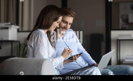 Happy colleagues using phone together, chatting, discussing news Stock Photo