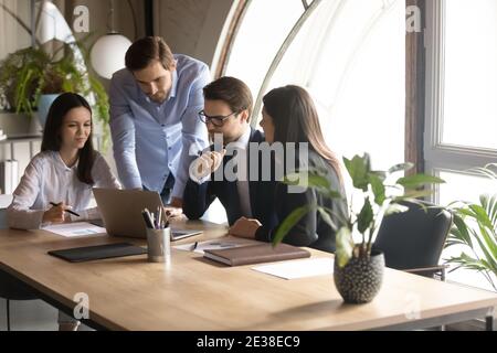 Diverse colleagues with team leader working on online project together Stock Photo