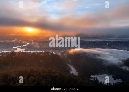 An aerial view of Launceston in Tasmania at dawn. The sun rises over the misty Tamar river. Stock Photo