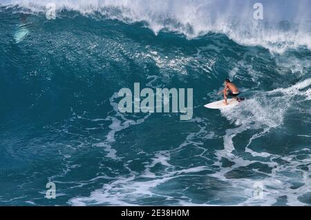Distant view of a lone surfer riding a large wave. Stock Photo