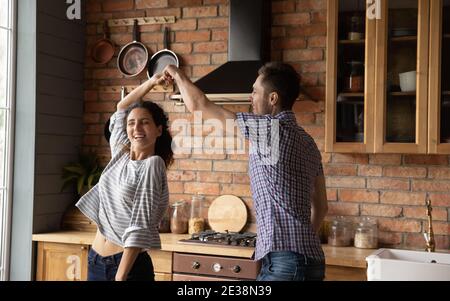 Overjoyed millennial couple dancing in new home kitchen Stock Photo
