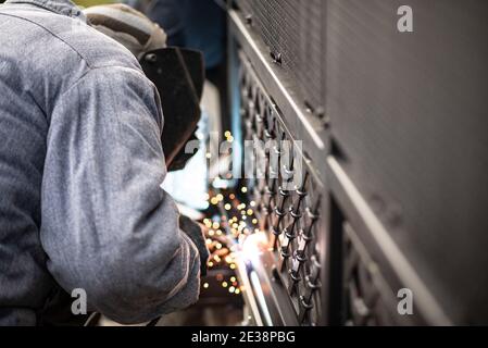 Professional worker performs work on start of sliding gate. Process of welding metal rack. Professional service of installation and maintenance of aut Stock Photo