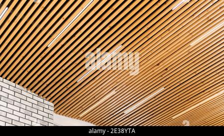 Close-up on a loft-style pine wood plank ceiling combined with white brick wall trim. The idea of ​​a ceiling design in a minimalist style. Original L Stock Photo