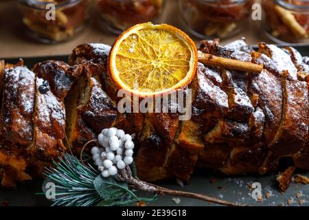 Sponge cake sliced, sprinkled with powdered sugar, decorated with cinnamon and orange slice. The concept of festive decoration. Stock Photo
