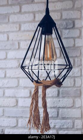 Pendant lamp creative, loft lamp, rope decor with a lamp in the interior against a white brick wall. Stock Photo