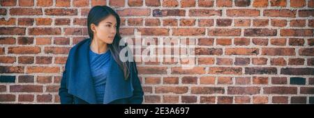 Asian woman banner portrait fashion model wearing autumn outerwear wool waterfall jacket on brick wall office wear style city lifestyle. Panoramic Stock Photo