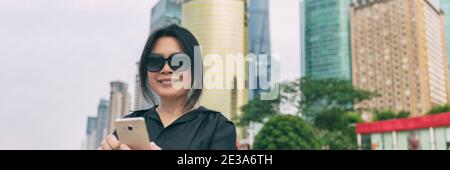 Phone Asian mature woman traveling using mobile 5g device on business trip travel city lifestyle panoramic banner. Elegant chinese lady with Stock Photo