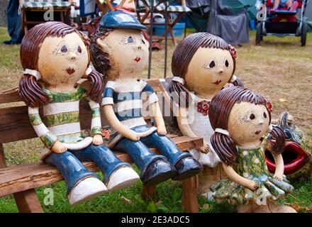 Family with children sitting on a bench. Ceramic marionettes. Traditional craft.