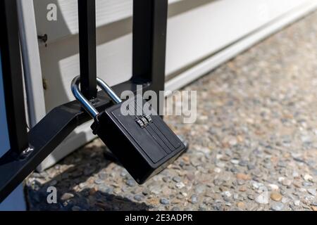A closed combination lock or padlock attached to an iron gate at a home. Stock Photo