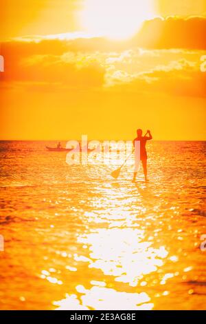 Hawaii ocean lifestyle - watersport activity on ocean - stand up paddleboard, people training on outrigger canoe . Active summer healthy living Stock Photo