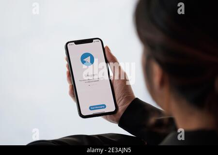 CHIANG MAI, THAILAND, JAN 18, 2021 : Woman hand holding iPhone 12 with social networking service Telegram on the screen. iPhone 12 was created and Stock Photo