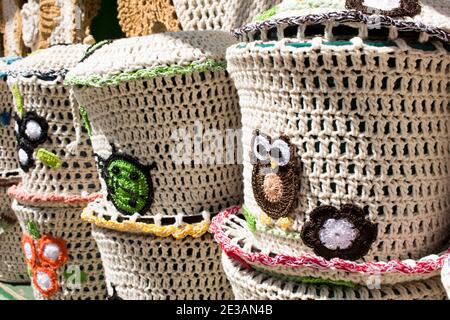 Crochet pieces for jars and trash bins with brown owl, green ladybug and colored flowers Stock Photo