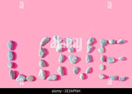 word love made of stones. Unusual spelling of the word love. Valentine's Day Confession. Ultimate Gray stones on a pale pink color. Pastel texture Stock Photo