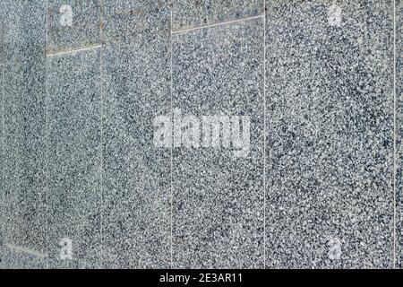 Full frame abstract texture background of a vintage exterior smooth granite stone wall surface, showing mild wear and staining from aging Stock Photo