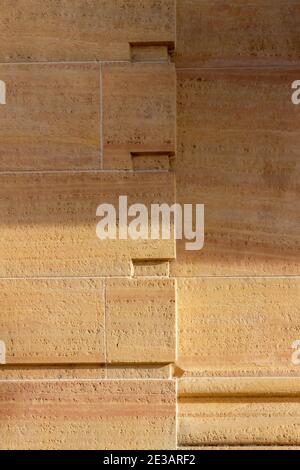 Full frame texture background of a modern natural stone wall with geometric design cutouts and lines, in natural sunlight with light shade Stock Photo
