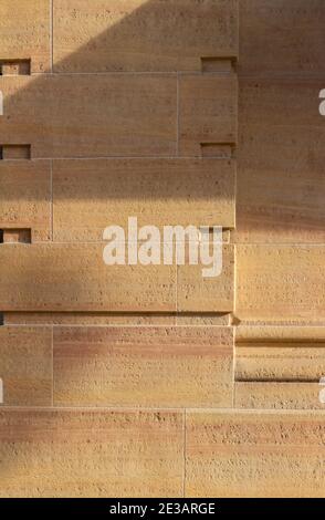 Full frame texture background of a modern natural stone wall with geometric design cutouts and lines, in natural sunlight with light shade Stock Photo