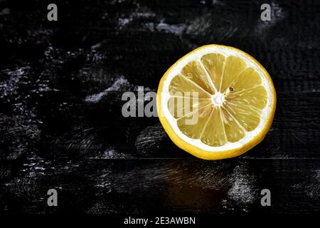 Fresh ripe lemons on dark stone background/ Half ripe lemon on a black background. Lemon cutaway. Vitamin C. Stock Photo