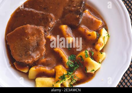 Pasticada With Gnocchi - Dalmatian Pot Roast or beef/ Croatian dish - Pasticada with gnocchi, beef stew in a sauce  at dark wooden background Stock Photo