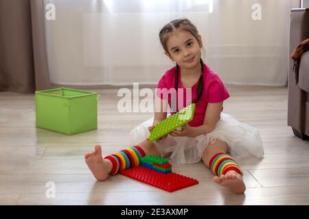 Girl play with multi-colored plastic constructor on floor in room Stock Photo