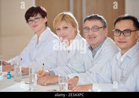 Researchers attending medical conference, taking notes and looking at camera Stock Photo