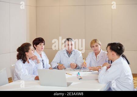 Group of serious researchers having emergency meeting and discussing side effects of new coronavirus vaccine Stock Photo