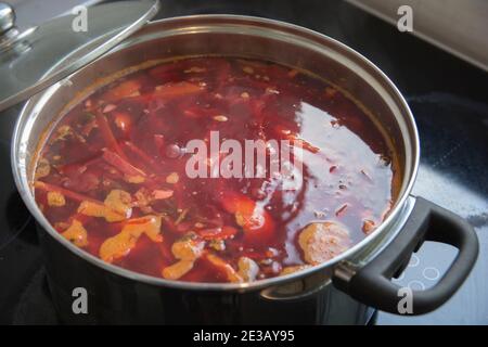 A boiling pot of traditional sour Borscht soup,  one of the most famous dishes of Ukrainian cuisine, made with beetroots as one of the main ingredient Stock Photo
