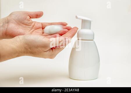 Hands of mature woman with foam of antibacterial soap on white background. Stock Photo