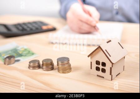 Stacks coins on wooden table with calculator. man using calculator calculating monthly home expenses, taxes, bank account balance payment, concept sav Stock Photo